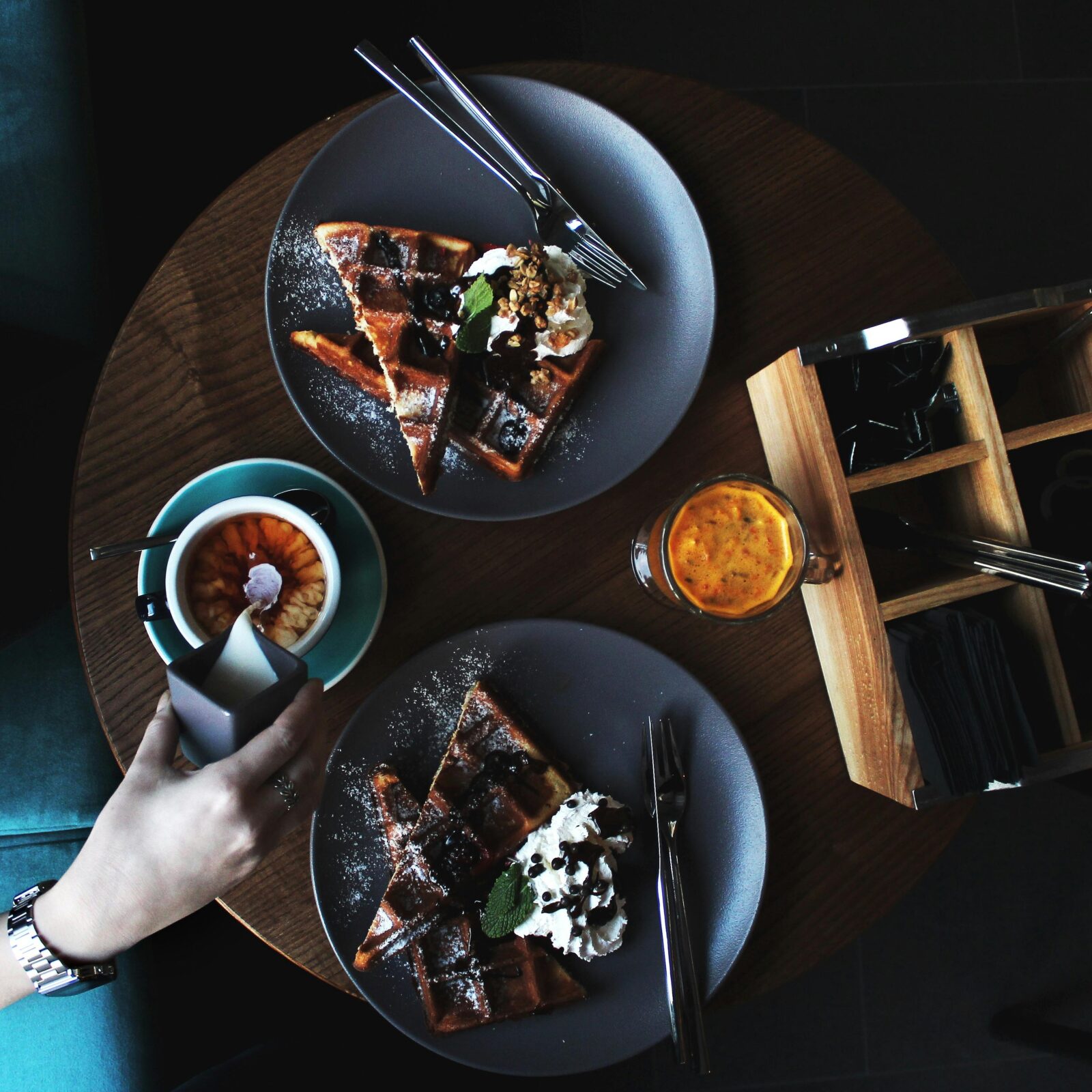 Top view of waffles, cappuccino, and juice on a wooden table for a delightful breakfast.